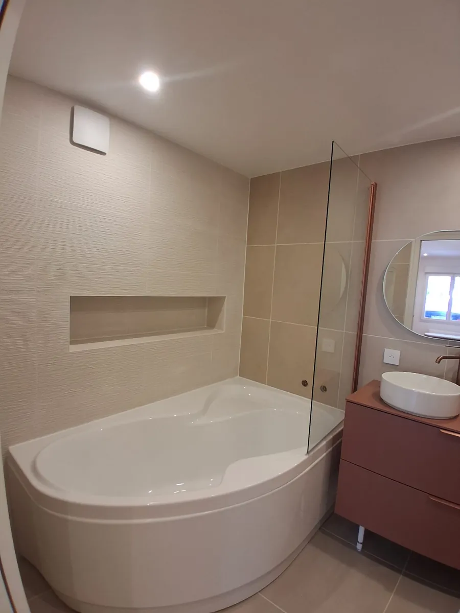 Baignoire d'angle avec niche murale carrelee et pare-bain vitre, salle de bain en Essonne