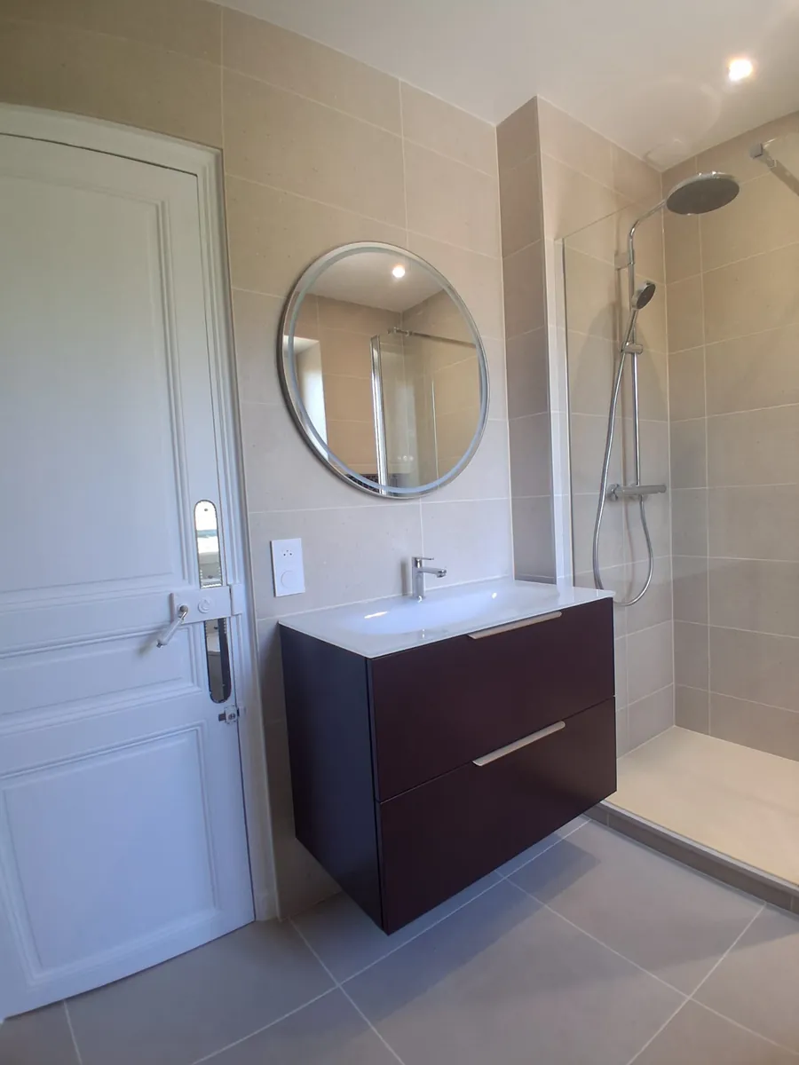 Meuble vasque suspendu et miroir rond dans une salle de bain renovee en Essonne
